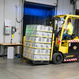 A warehouse employee operating a forklift to move stocked goods indoors. Perfect for industry and logistics visuals.