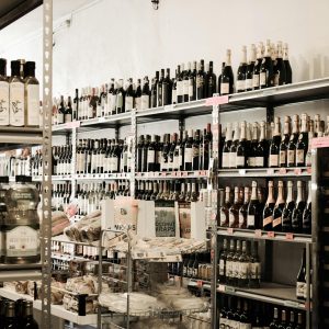 A neatly organized liquor aisle with various wine and oil bottles on shelves.